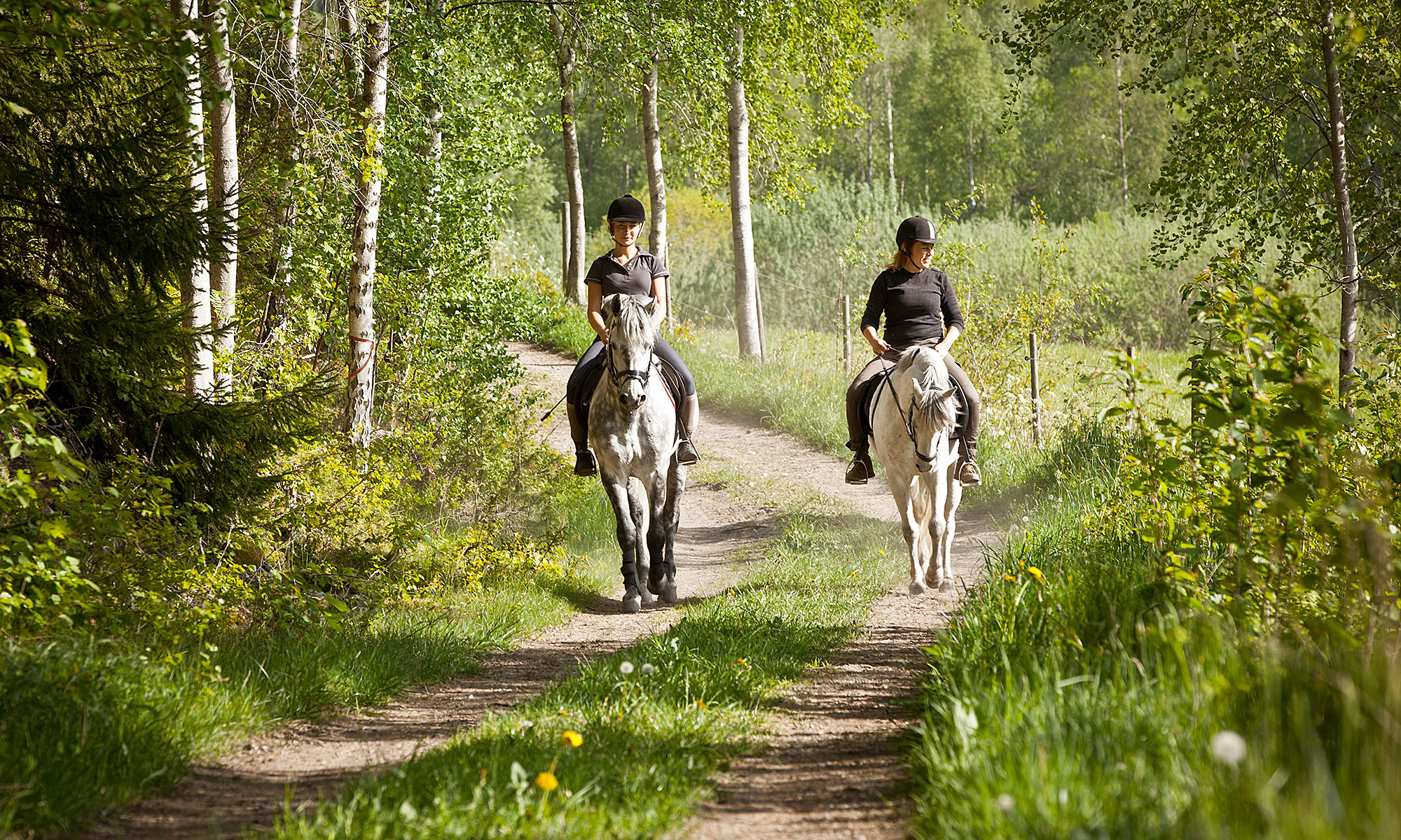Marie och hennes dotter rider på varsin häst